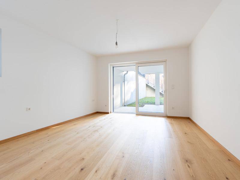 Heller Raum mit Holzboden und Zugang zu einem kleinen Außenbereich.
