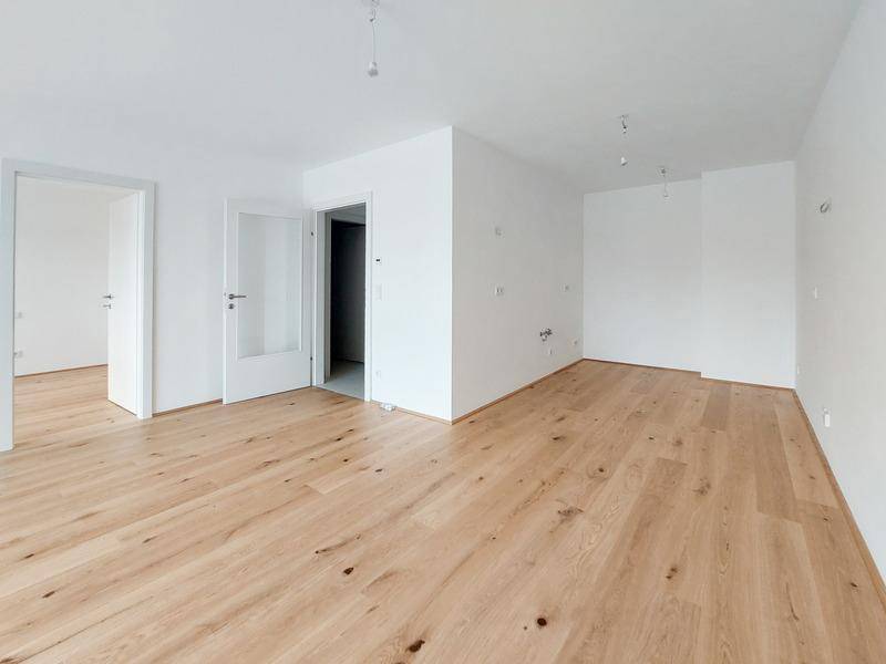 Heller Wohnraum mit neuem Holzplankenboden und weißen Wänden, bereit zum Einzug.