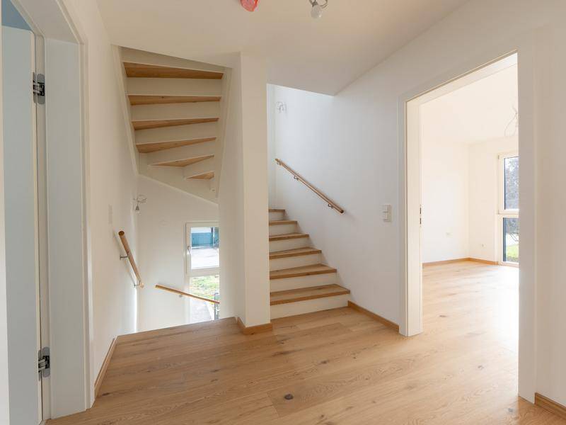 Heller Flur mit Holztreppe, die die verschiedenen Etagen des Hauses verbindet.