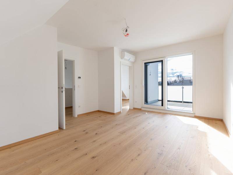 Helles Zimmer mit Holzboden, Klimaanlage und Zugang zu einem privaten Balkon.