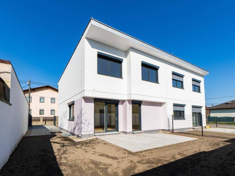 Rückseite eines modernen Hauses mit Terrasse und Gartenbereich, bereit zur Gestaltung.