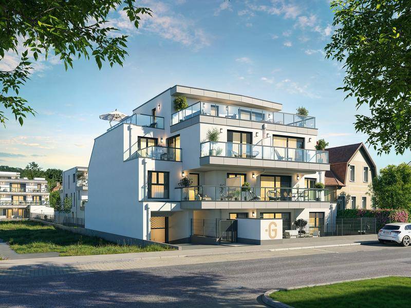 Moderne Wohnanlage mit mehreren Etagen und Balkonen unter blauem Himmel.