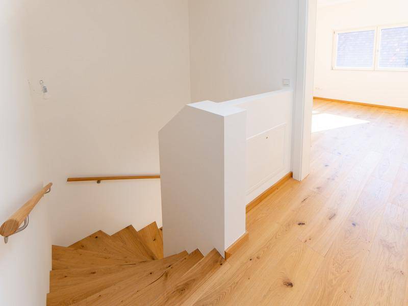 Moderne Holztreppe mit hellem Geländer, die die Stockwerke des Hauses verbindet.