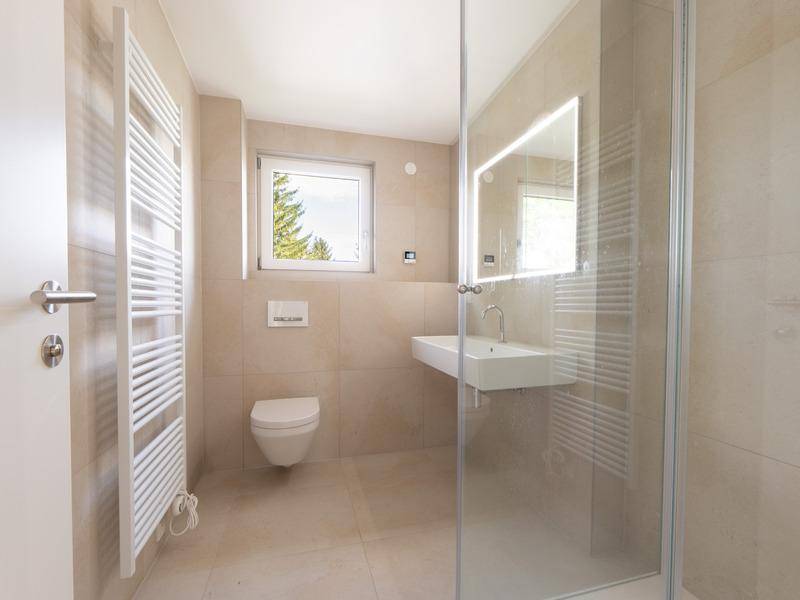 Modernes Badezimmer mit begehbarer Dusche, Wand-WC, Einzelwaschbecken und Handtuchheizkörper.