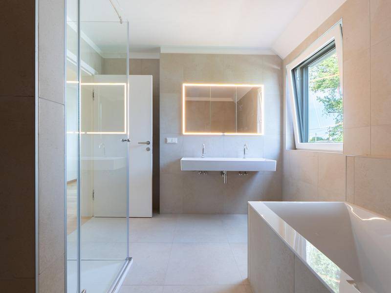 Modernes Badezimmer mit begehbarer Dusche, Badewanne, Doppelwaschbecken und Fenster.