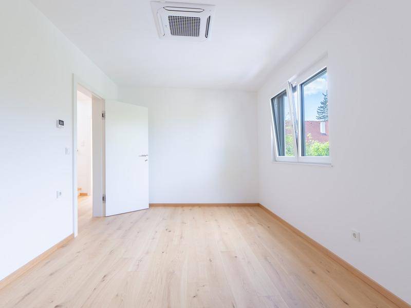Leeres Zimmer mit hellem Holzboden und Fenster, bereit zur individuellen Gestaltung.