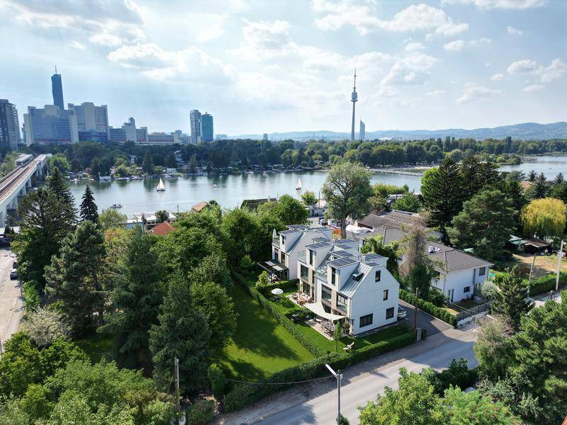 Luftaufnahme einer modernen Wohnanlage mit Blick auf die Stadt und einen See.