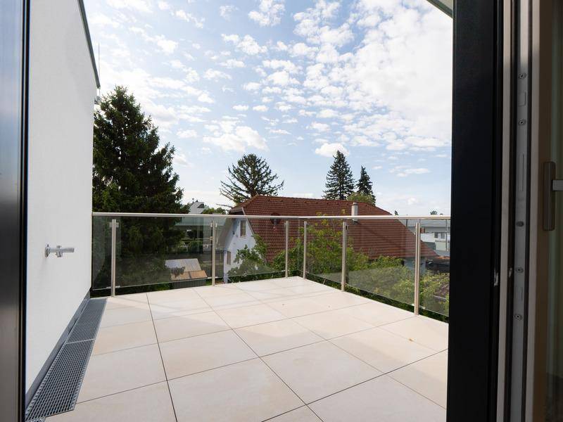 Heller Balkon mit Glasgeländer und Blick auf die umliegende Wohngegend.