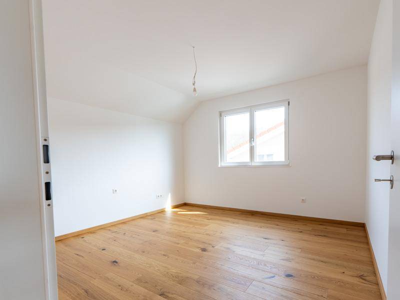 Leeres Schlafzimmer mit Eichenparkett, weiß gestrichenen Wänden und Fenster.