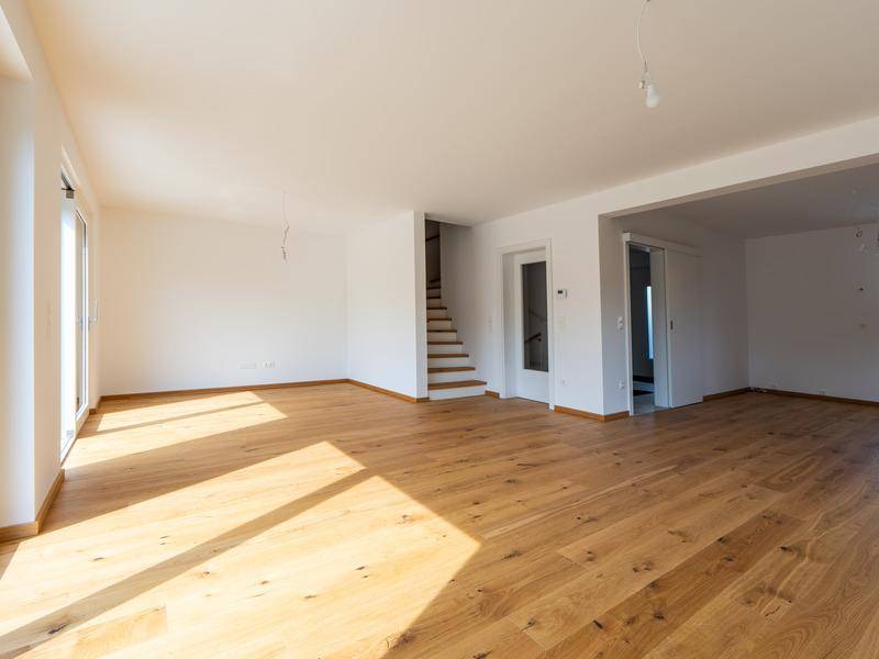 Geräumiges Wohnzimmer mit hellem Eichenparkett, großen Fenstern und viel Tageslicht.