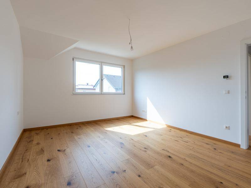 Helles Schlafzimmer mit Eichenparkett, weiß gestrichenen Wänden und Dachschräge.
