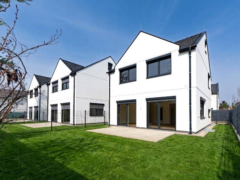 Reihenhäuser mit moderner Architektur, weißer Fassade, schwarzem Dach und Rasenfläche.