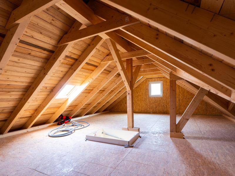 Unausgebauter Dachboden mit sichtbaren Holzbalken, Dachschräge und Dachfenstern.