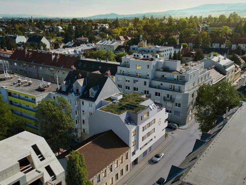 Luftaufnahme eines modernen Neubaus mit begrüntem Dach in städtischer Umgebung.