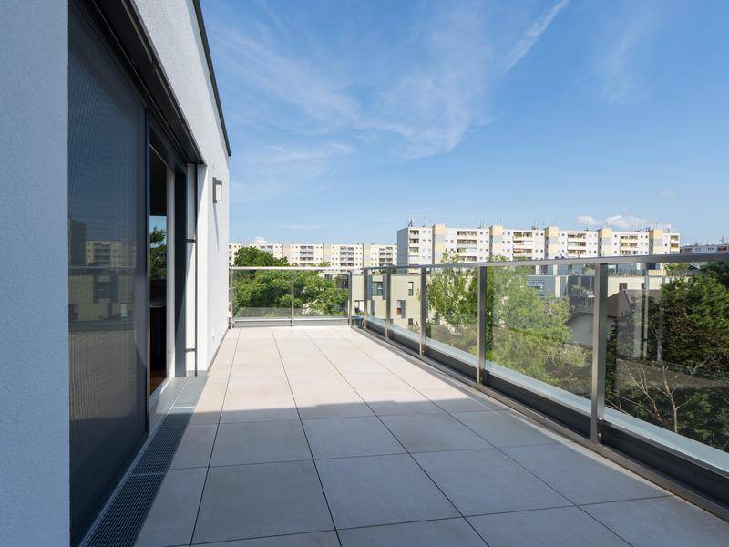 Geräumiger Balkon mit Fliesenboden und Glasgeländer, bietet einen weiten Blick über die Stadt.