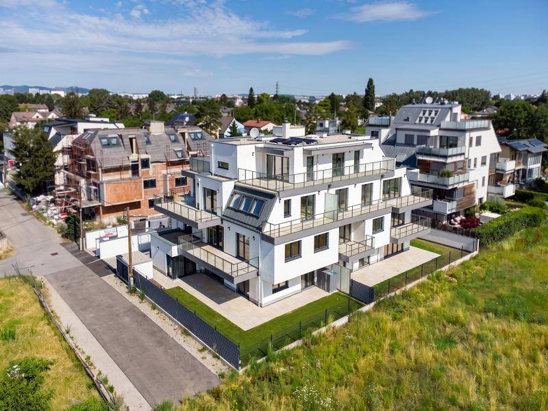 Moderne Wohnanlage mit mehreren Balkonen und Terrassen, umgeben von Grünflächen.