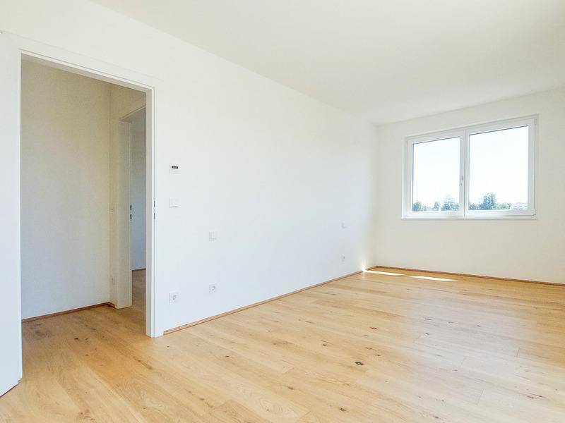 Geräumiges Schlafzimmer mit Holzboden und großen Fenstern, bietet viel Tageslicht.