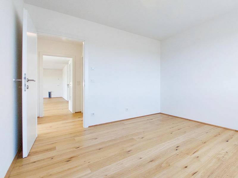 Helles Schlafzimmer mit Holzboden und weiß gestrichenen Wänden, bereit zum Einzug.