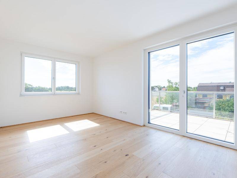 Lichtdurchflutetes Schlafzimmer mit Zugang zu einem großen Balkon und weitem Ausblick.