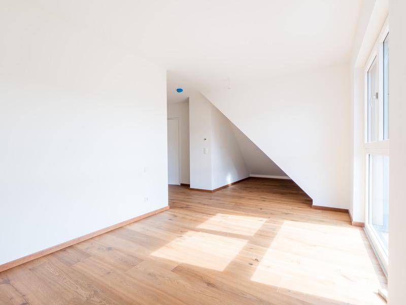 Helles Zimmer mit Eichenparkett, weißen Wänden und Dachschräge.