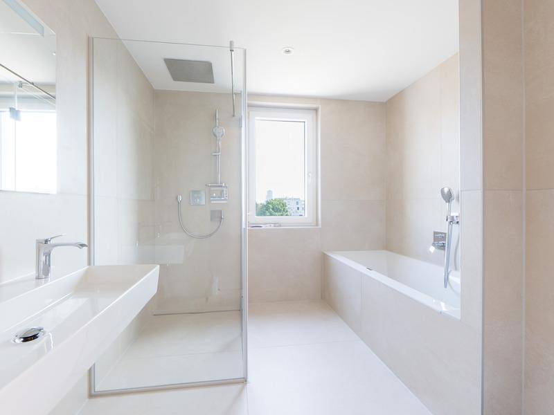 Modernes Badezimmer mit begehbarer Dusche, Badewanne und großem Fenster.
