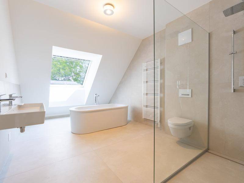 Modernes Badezimmer mit freistehender Badewanne, begehbarer Dusche und Dachfenster.
