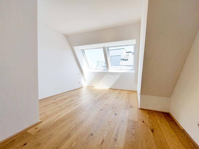 Lichtdurchflutetes Zimmer im Dachgeschoss mit Holzboden und großen Dachfenstern.