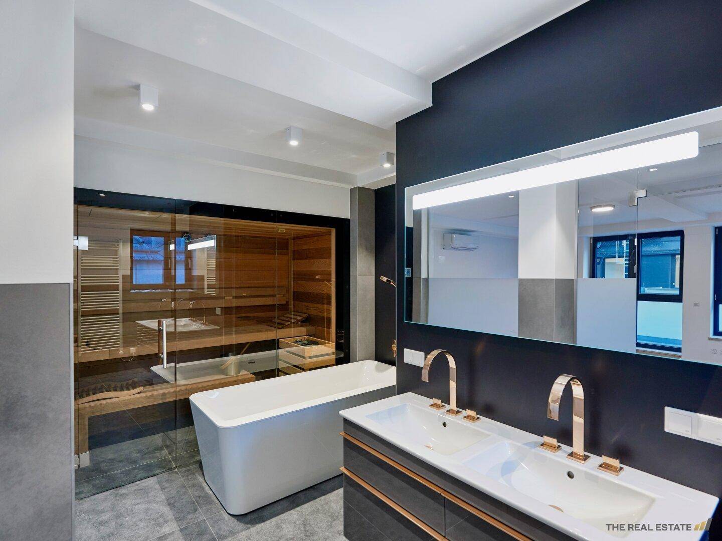 Luxuriöses Badezimmer mit Doppelwaschbecken, freistehender Badewanne und integrierter Sauna.