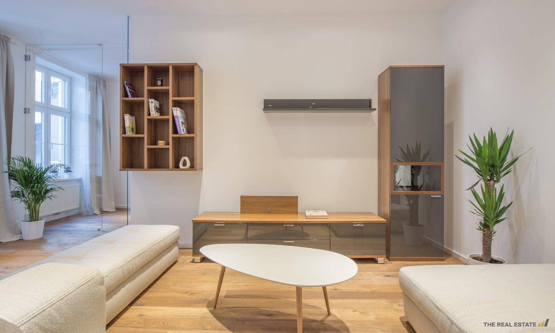 Moderner Wohnbereich mit Holzboden, stilvollen Möbeln und dekorativen Regalen.