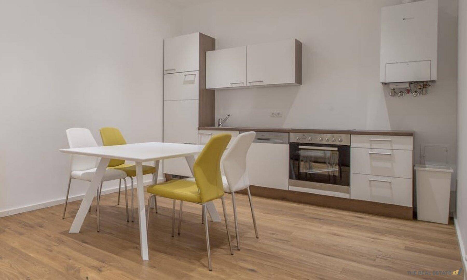 Funktionale Küche mit Essbereich, weißen Schränken und modernen Geräten.