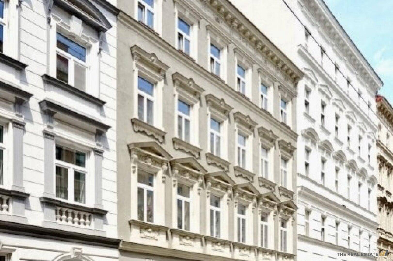Historische Gebäudefassade mit aufwendigen Verzierungen und großen Fenstern in der Stadt.