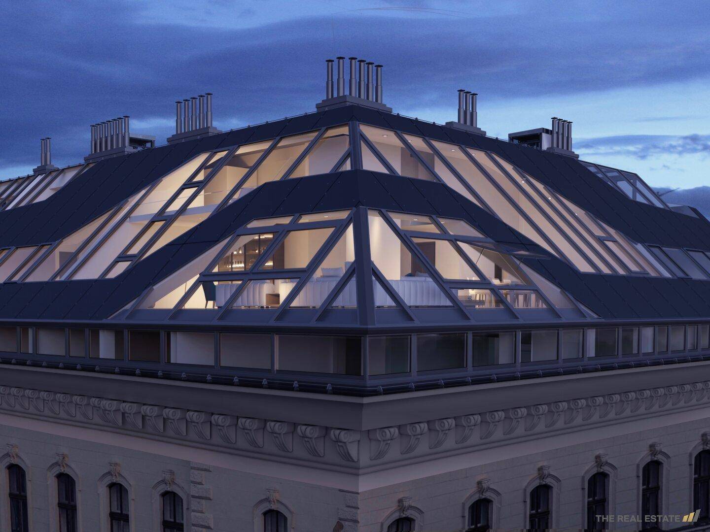 Architektonisch anspruchsvoller Dachausbau mit großen Glasflächen auf einem historischen Gebäude bei Nacht.