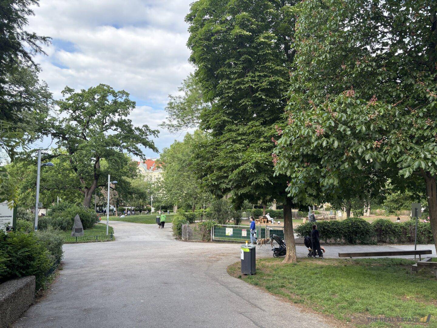 Grüne Parkanlage mit alten Bäumen, Spazierwegen und Erholungssuchenden.
