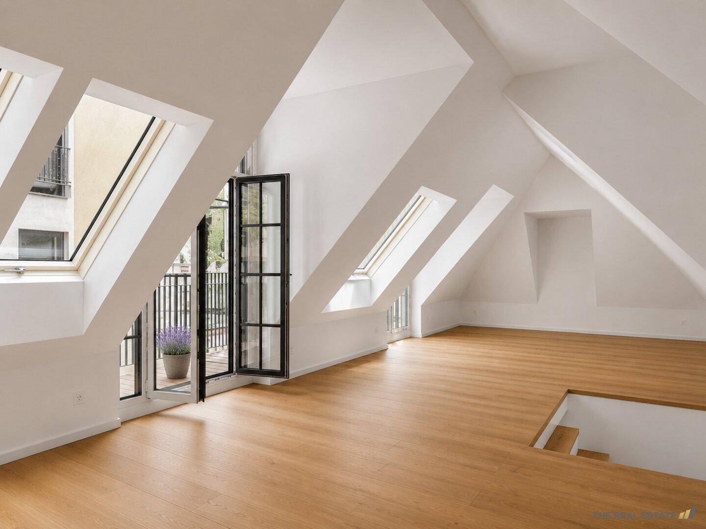 Lichtdurchfluteter Dachbodenbereich mit Holzboden, Dachschrägen und Zugang zu einem kleinen Balkon.