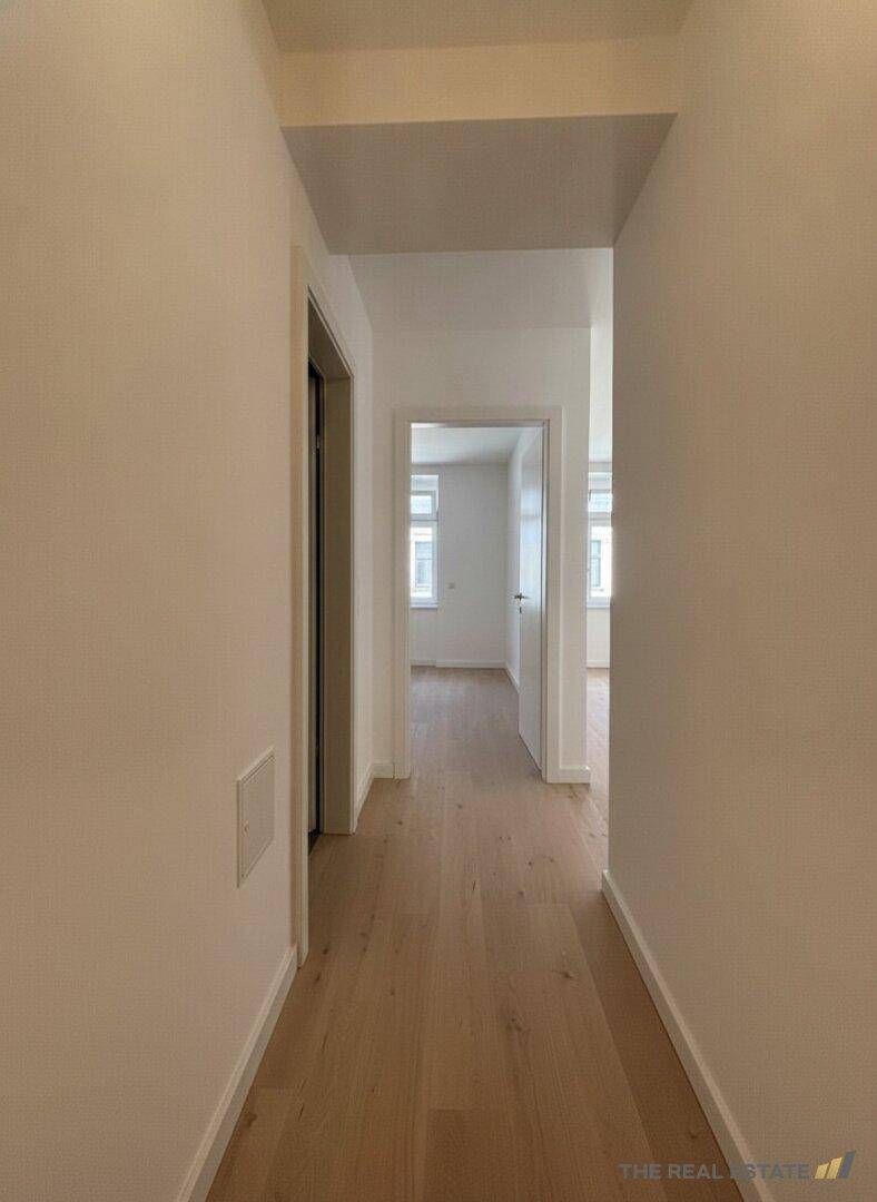 Langer, heller Flur mit Holzboden, der zu verschiedenen Räumen führt.