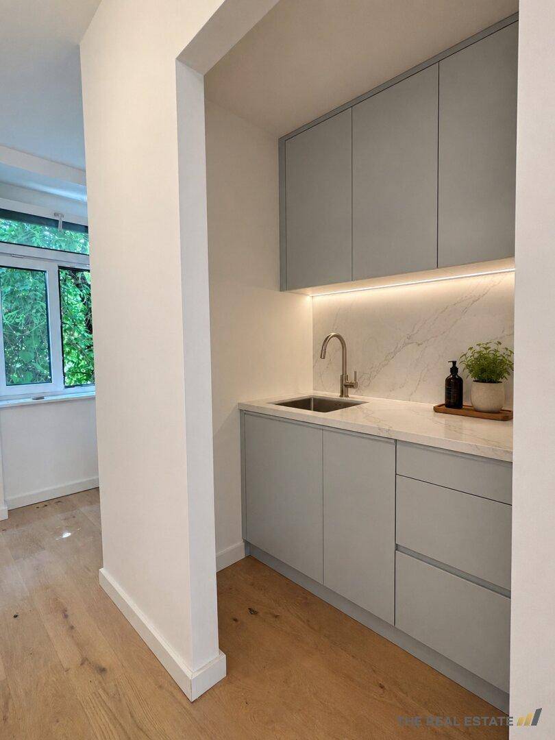Moderne Küchenzeile oder Hauswirtschaftsbereich mit Spüle, Marmor-Arbeitsplatte und Holzfußboden.
