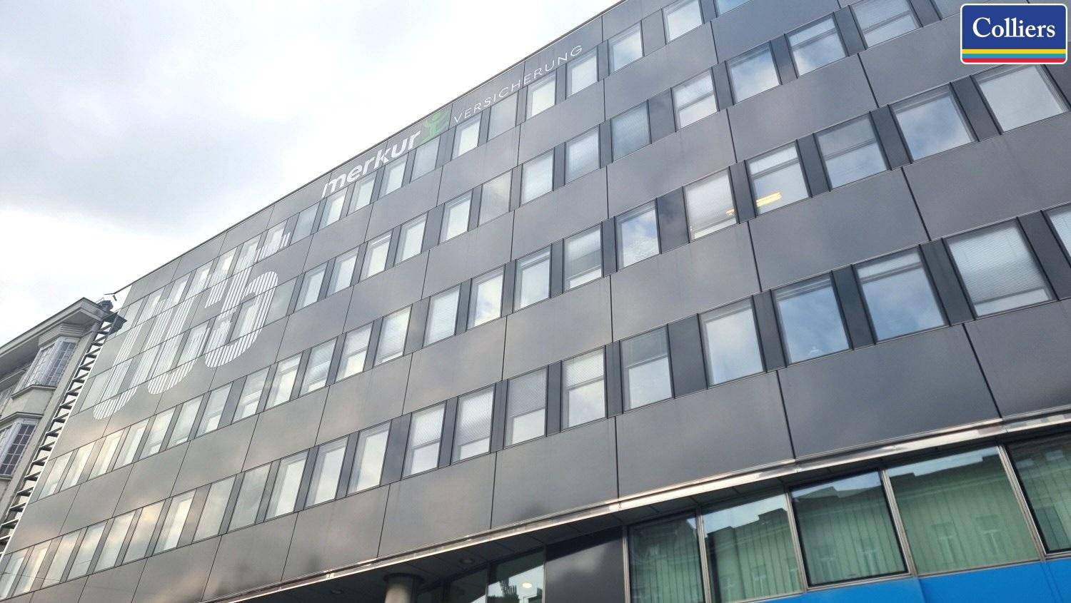 Moderne Bürogebäude-Fassade mit vielen Fenstern und Firmenlogo, prägt das Stadtbild.
