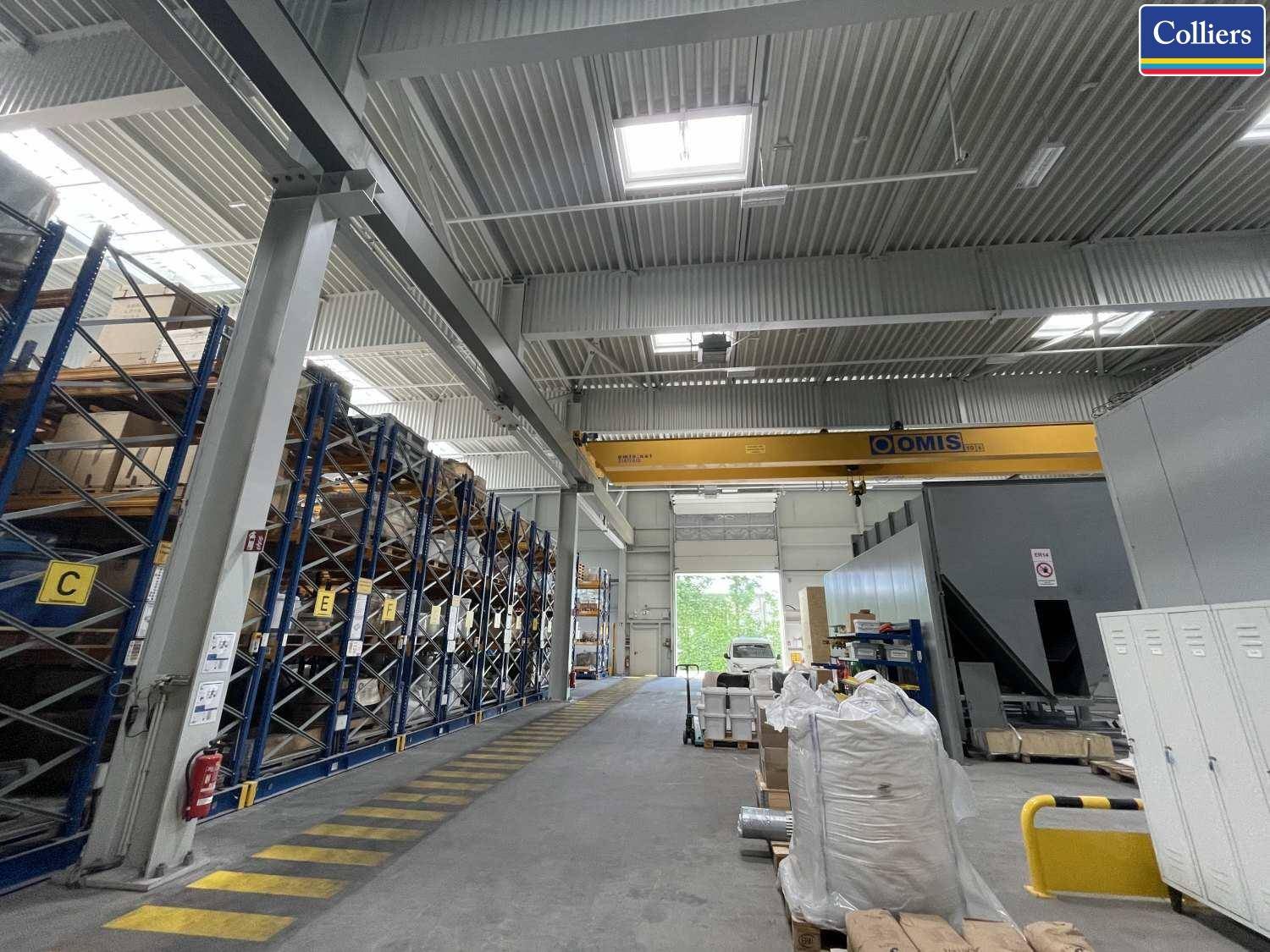 Große Lagerhalle mit hohen Regalen, einem gelben Kran und einem Blick auf den Ausgangsbereich.