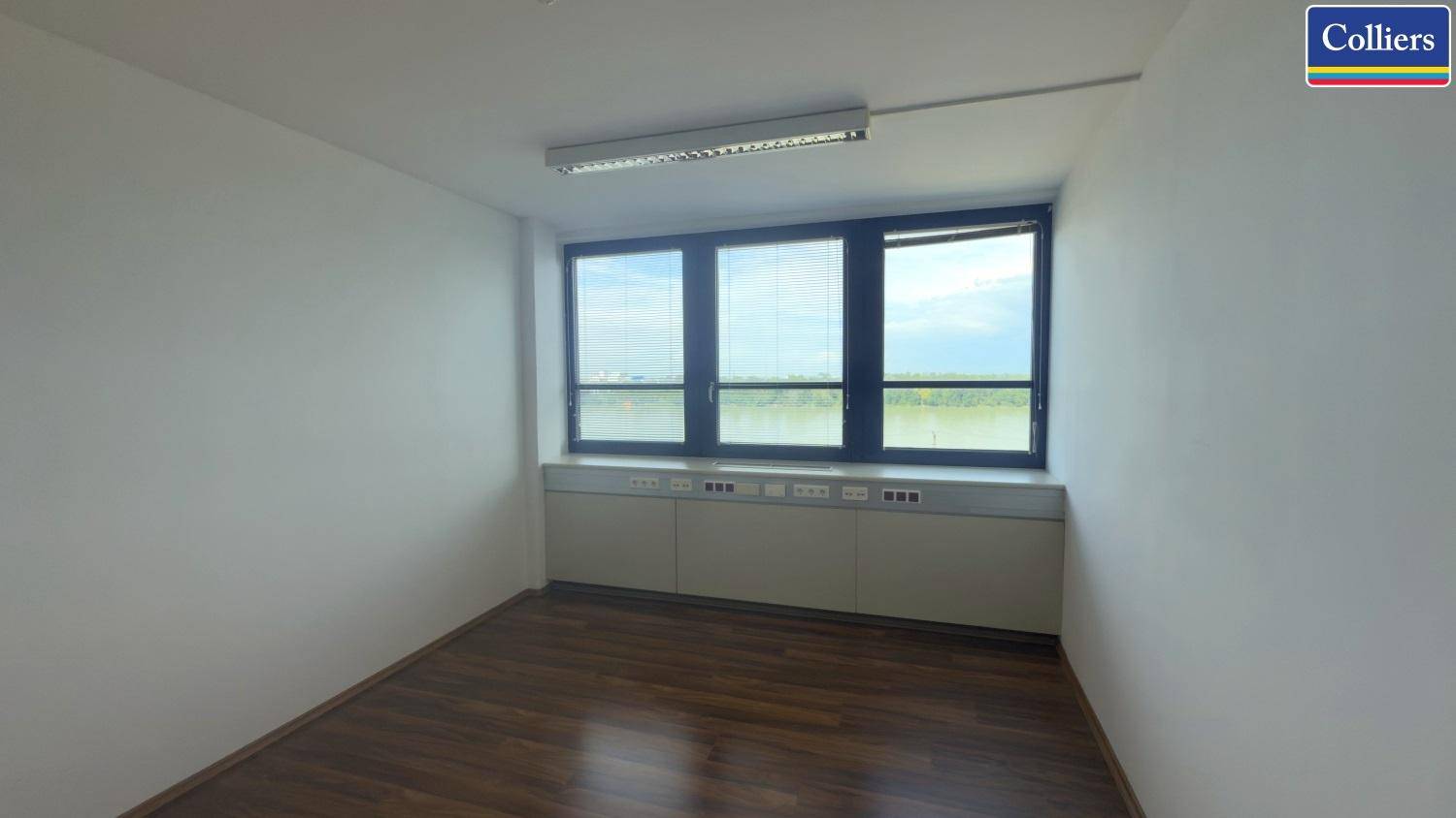 Helles Büro mit Holzboden und einer Fensterfront, die einen weiten Blick auf die Landschaft bietet.