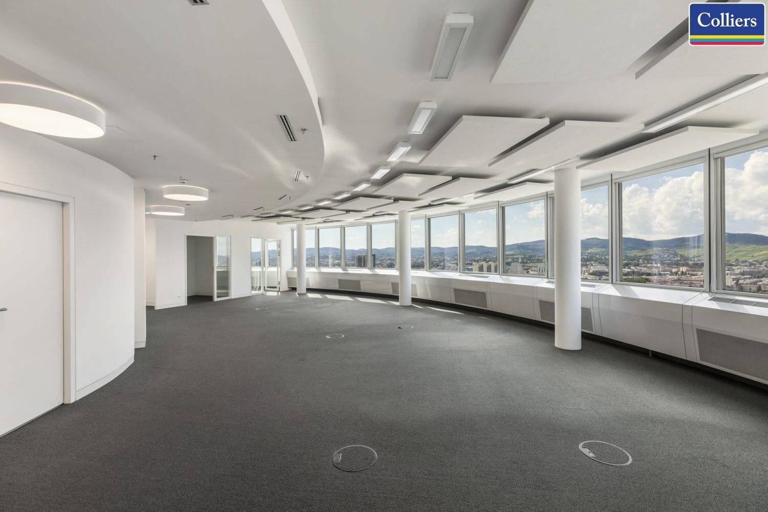 Großer, offener Bürobereich mit geschwungener Architektur und vielen Fenstern für eine helle Arbeitsumgebung.