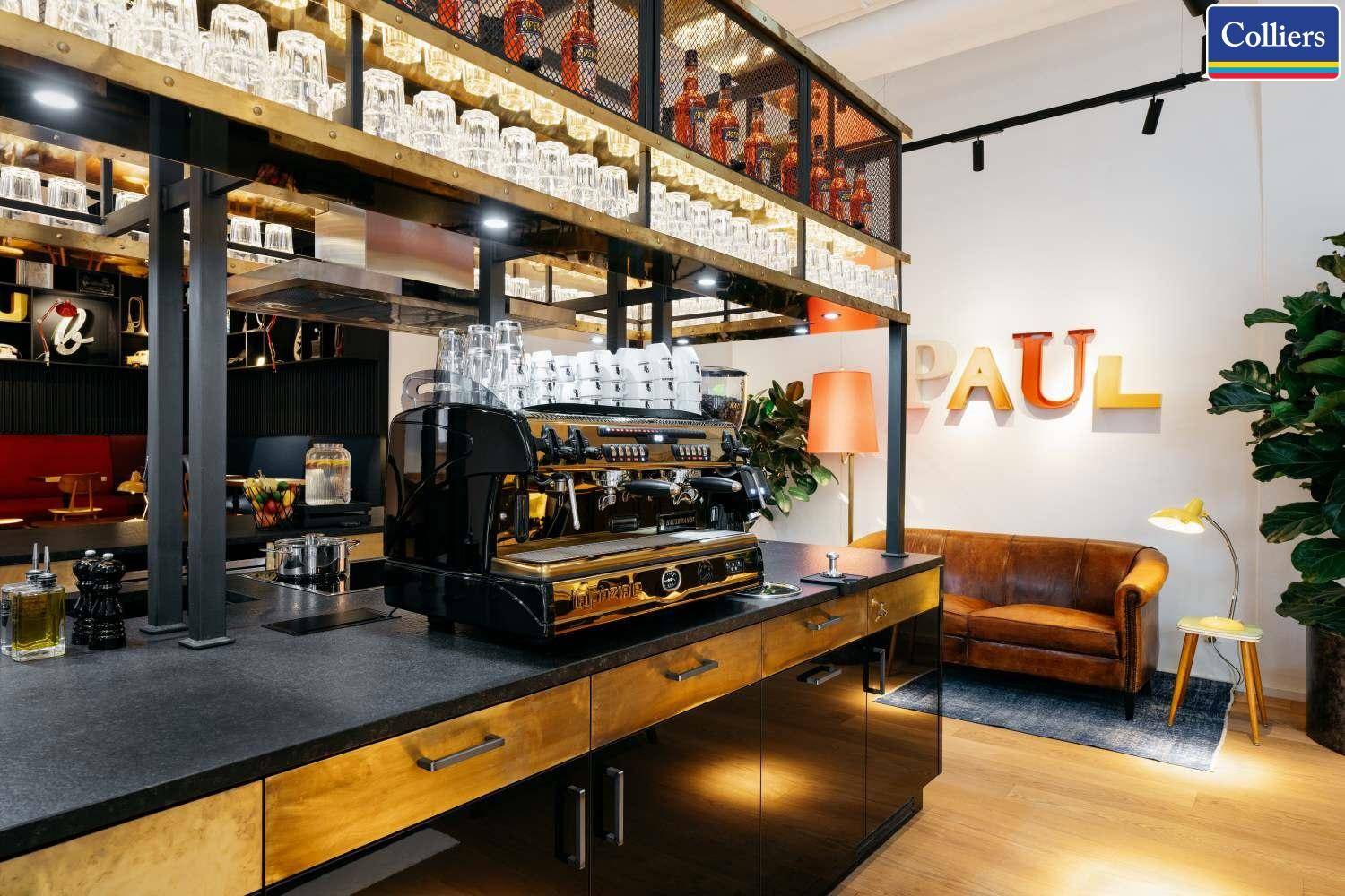 Professionelle Kaffeebar mit Espressomaschine, Gläserregal und gemütlicher Sitzecke im Hintergrund.