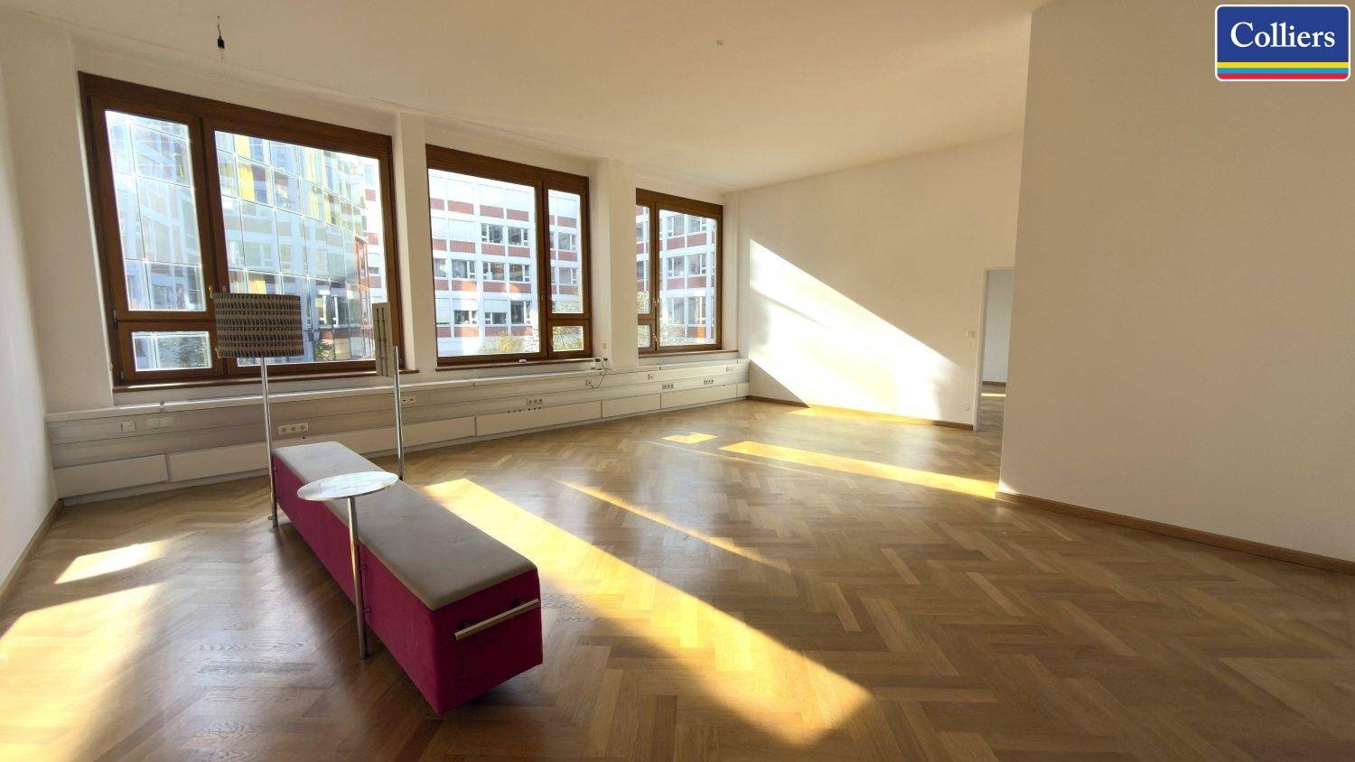 Geräumiger Büroraum mit natürlichem Lichteinfall und Blick auf umliegende Gebäude.