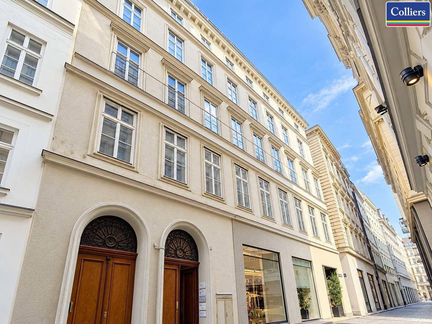 Historisches Gebäude mit klassischer Fassade, großen Fenstern und Geschäften im Erdgeschoss.