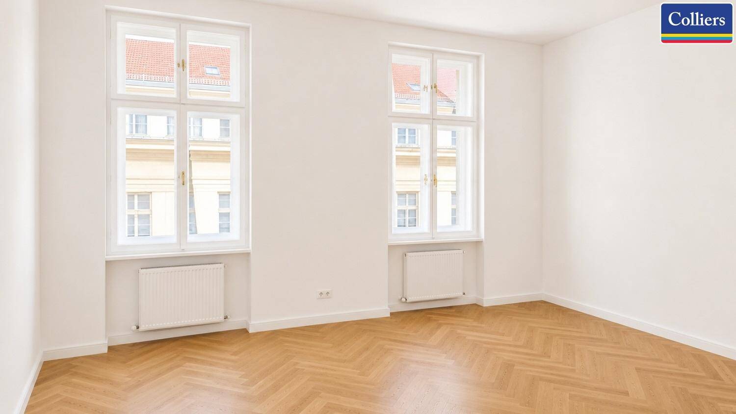 Freundlicher Raum mit zwei hohen Fenstern und Fischgrätparkett, perfekt für ein helles Arbeitsumfeld.
