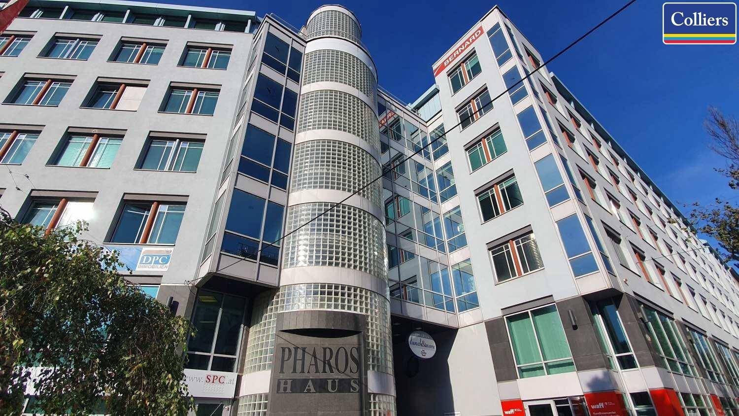 Moderne Bürogebäude-Fassade mit vielen Glasflächen und einem markanten runden Treppenhaus aus Glasbausteinen.