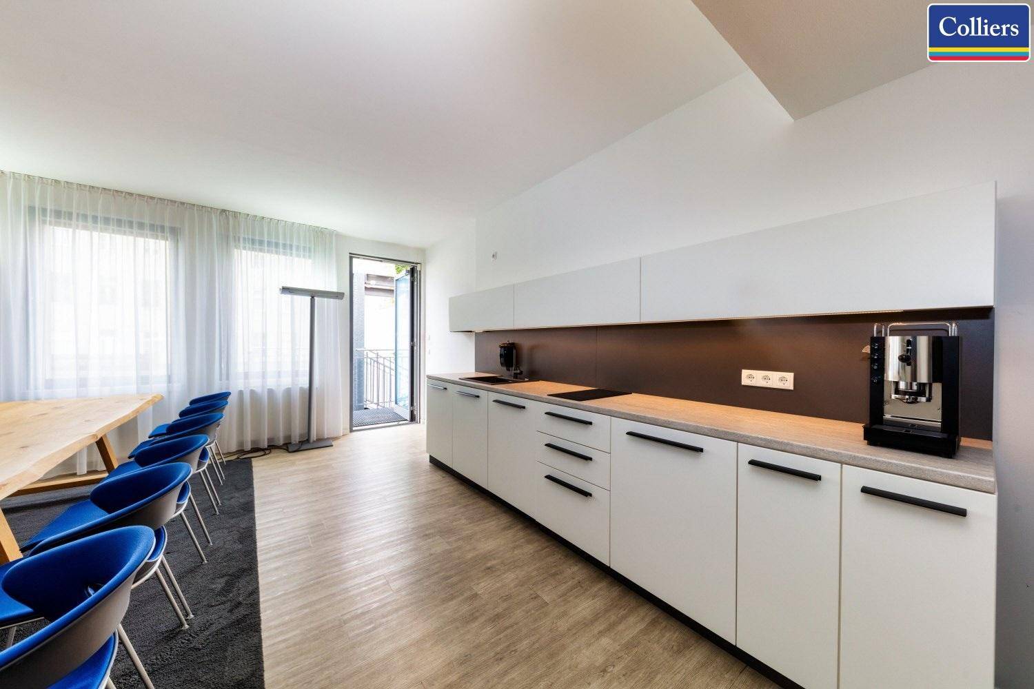 Moderne Einbauküche mit weißen Schränken, dunkler Arbeitsplatte und integrierter Kaffeemaschine.