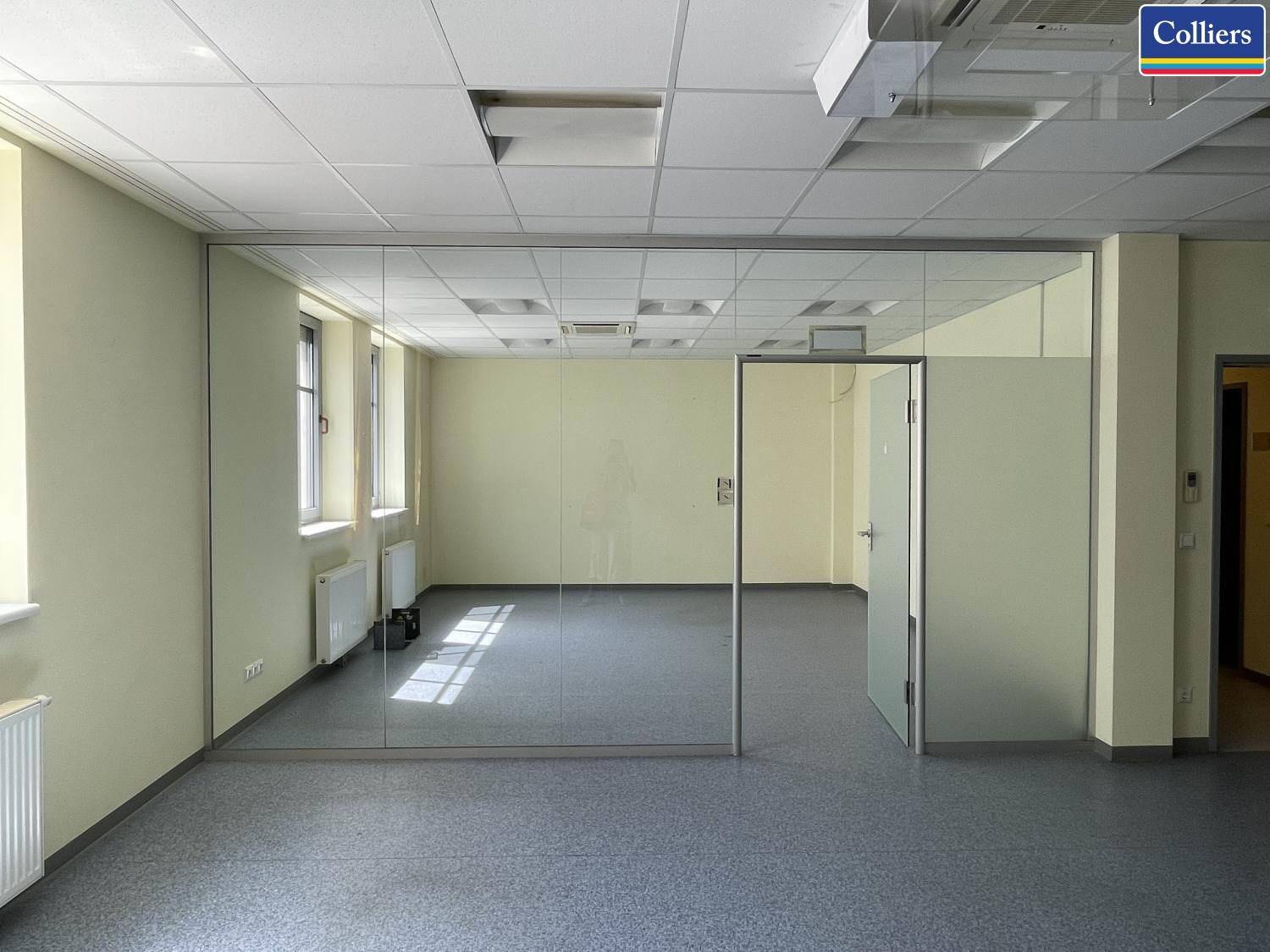 Leeres Büro mit Glaswänden, die einen separaten Bereich abtrennen, und Teppichboden.