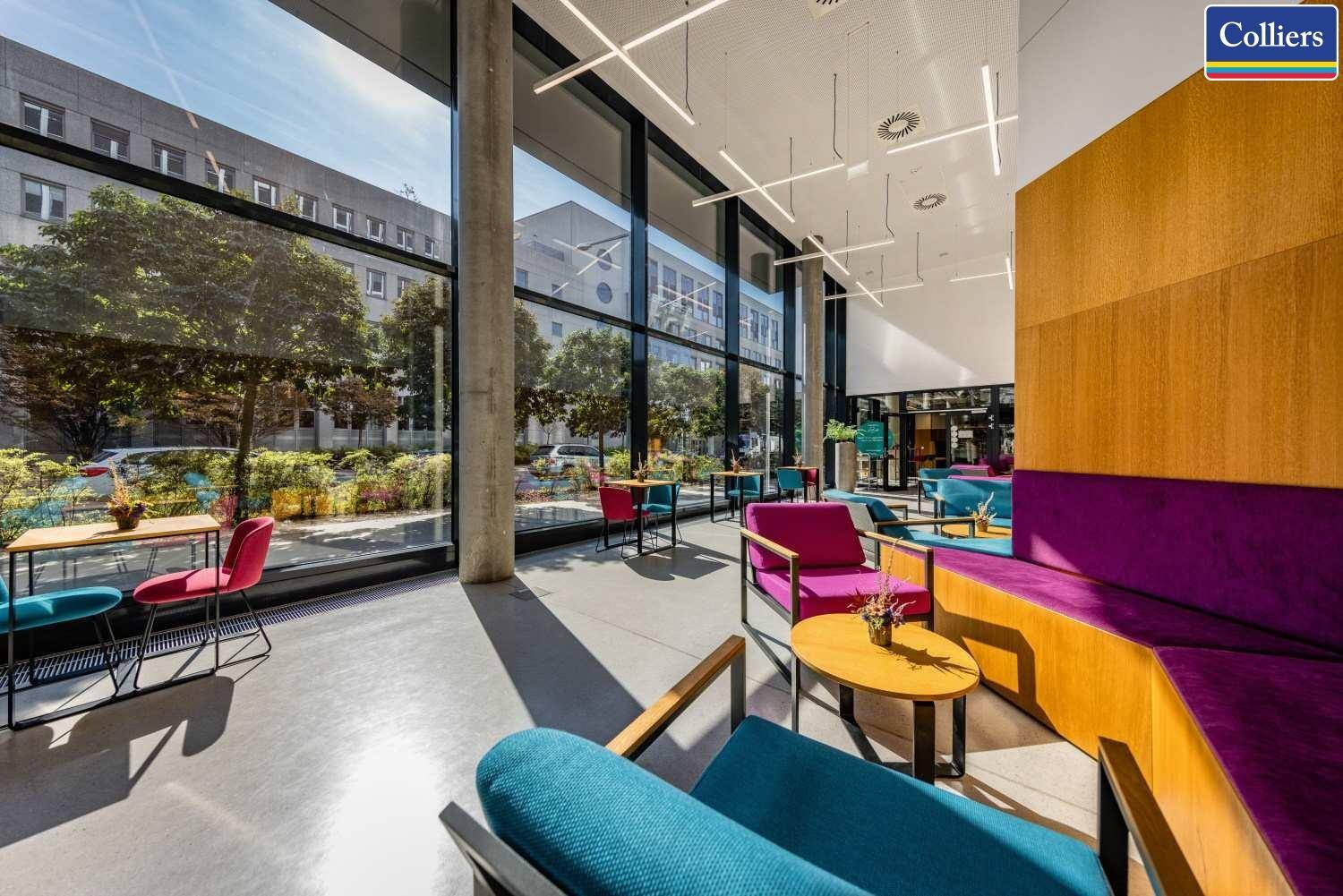 Farbenfrohe Lounge-Ecke mit modernen Möbeln, großen Fenstern und viel Tageslicht.