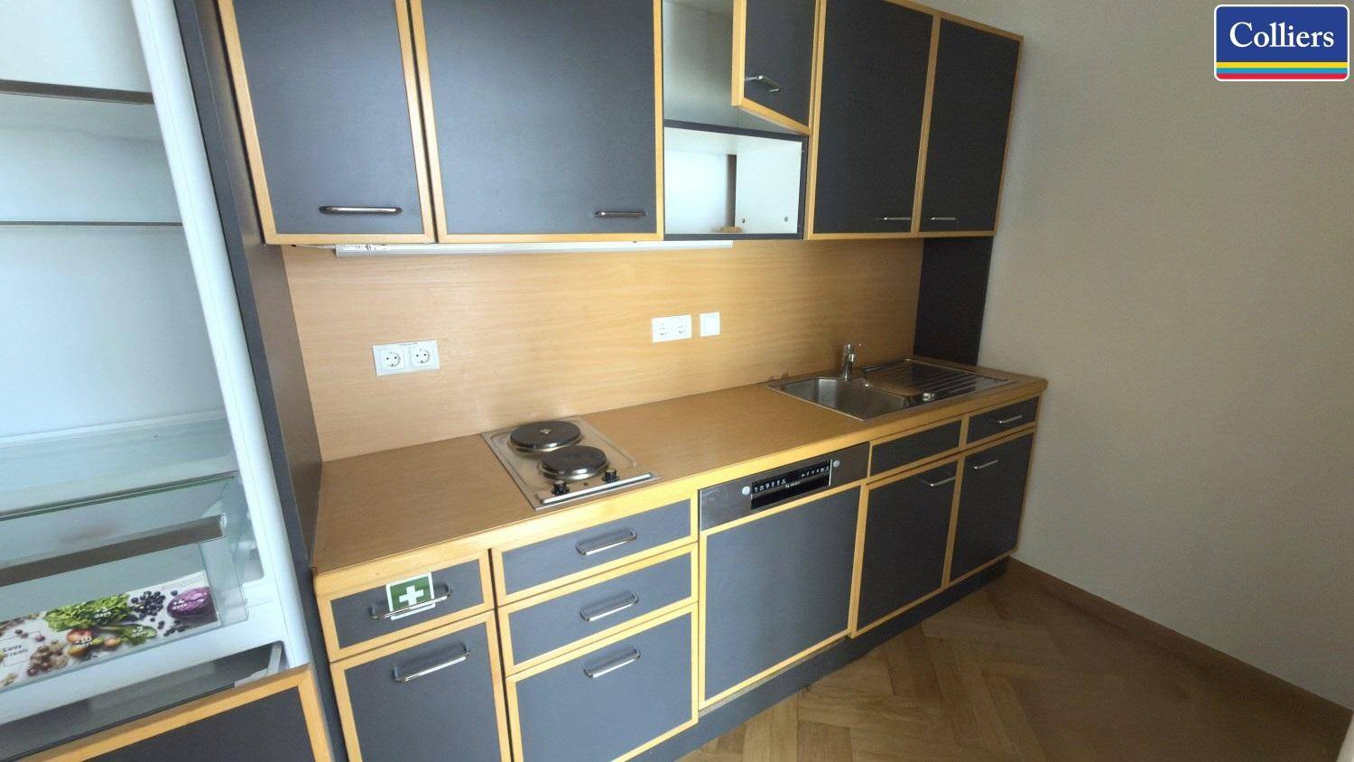 Kompakte Küchenzeile mit Kochfeld, Spüle und integriertem Kühlschrank, ideal für Büroräume.