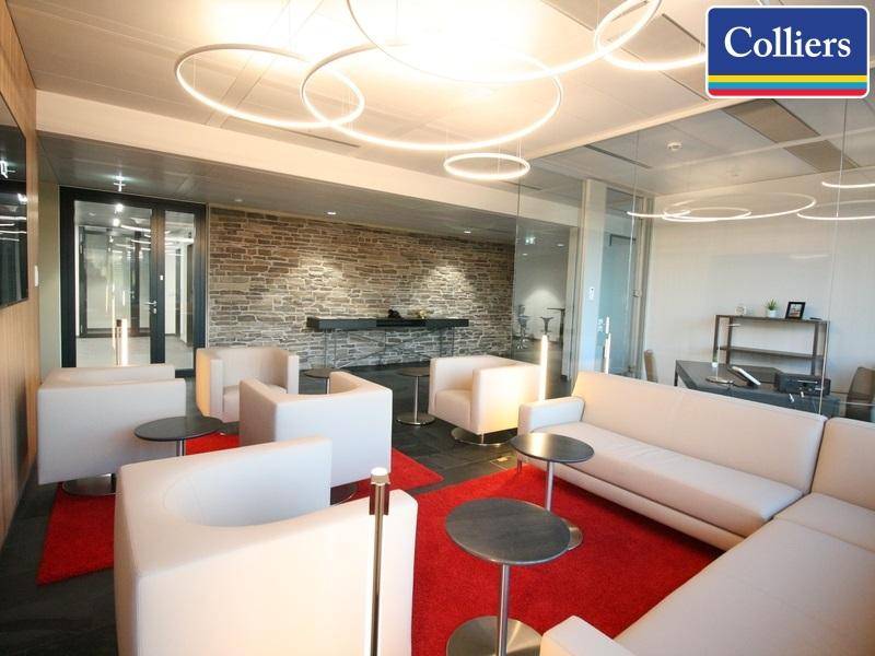 Stilvoller Loungebereich mit weißen Sofas, roten Teppichen und einer markanten Steinwand im Hintergrund.